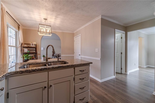 kitchen with dark wood-type flooring, decorative light fixtures, sink, and stone counters