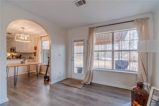 doorway to outside featuring ornamental molding, a wealth of natural light, and light wood-type flooring