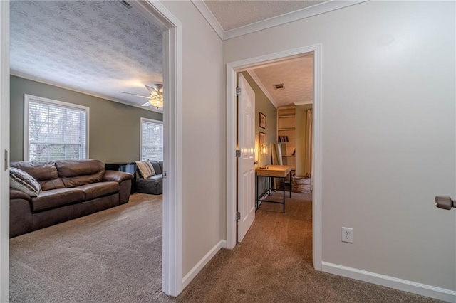 hall with crown molding, a textured ceiling, and carpet flooring