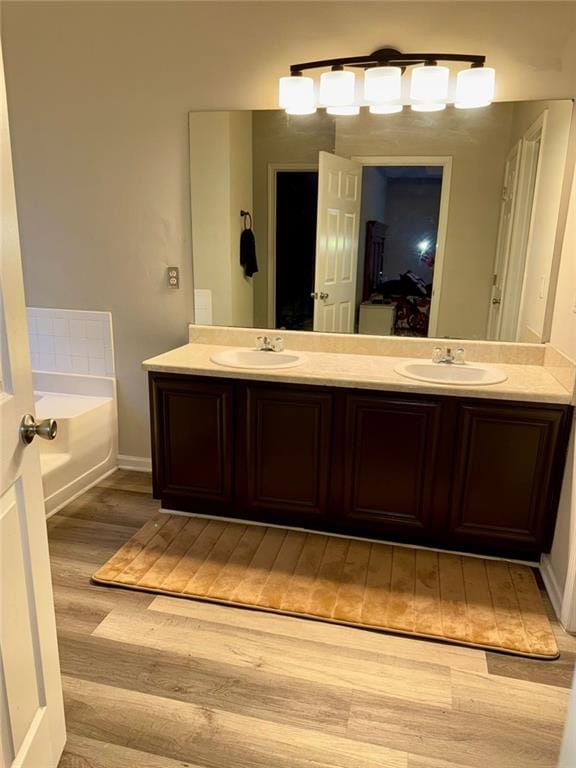 bathroom featuring wood-type flooring, vanity, and a tub