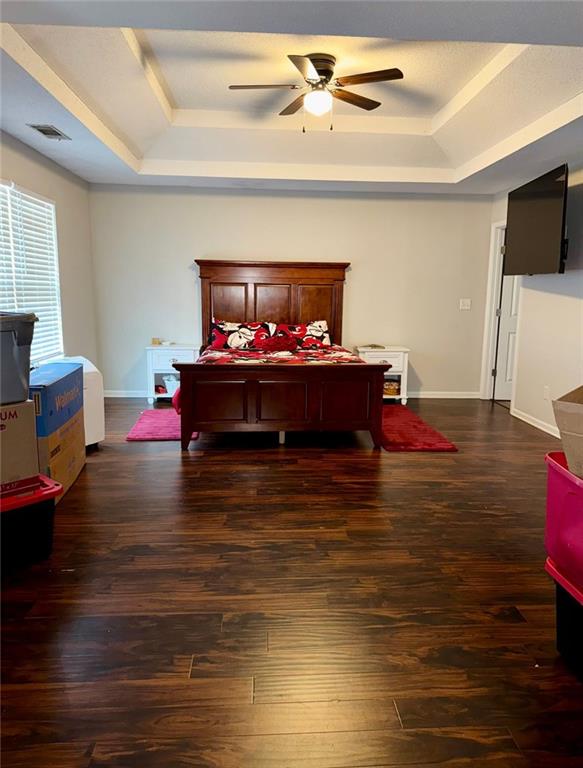 bedroom with a tray ceiling, ceiling fan, and dark hardwood / wood-style floors