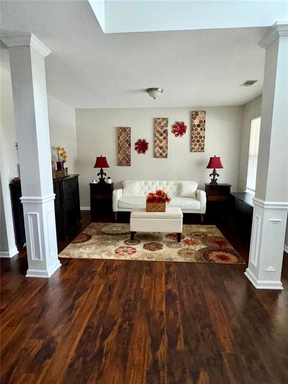 living room with dark hardwood / wood-style floors and decorative columns