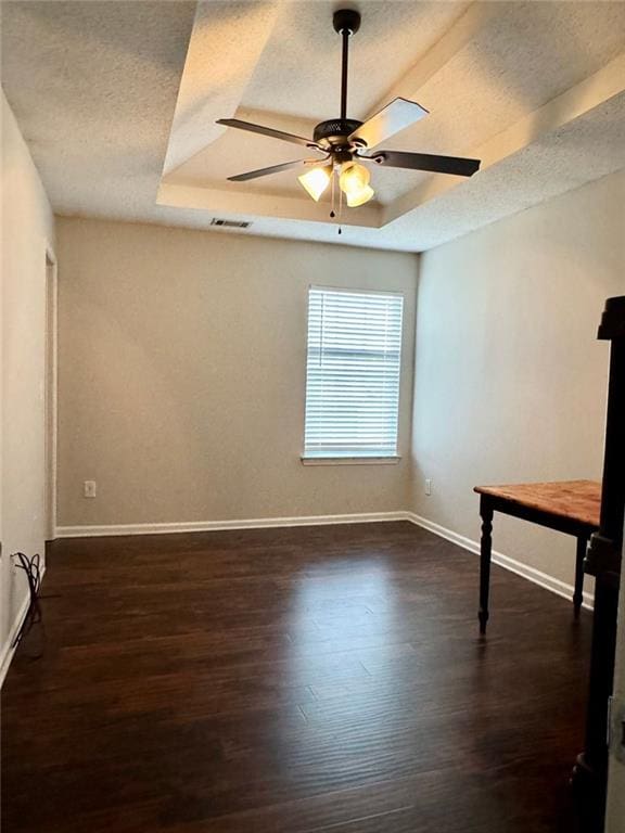 spare room with a tray ceiling, ceiling fan, a textured ceiling, and dark hardwood / wood-style floors