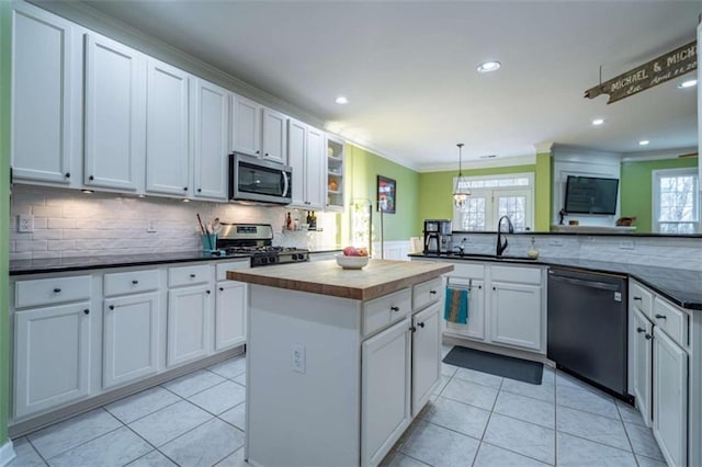 kitchen featuring light tile patterned flooring, appliances with stainless steel finishes, sink, white cabinets, and hanging light fixtures