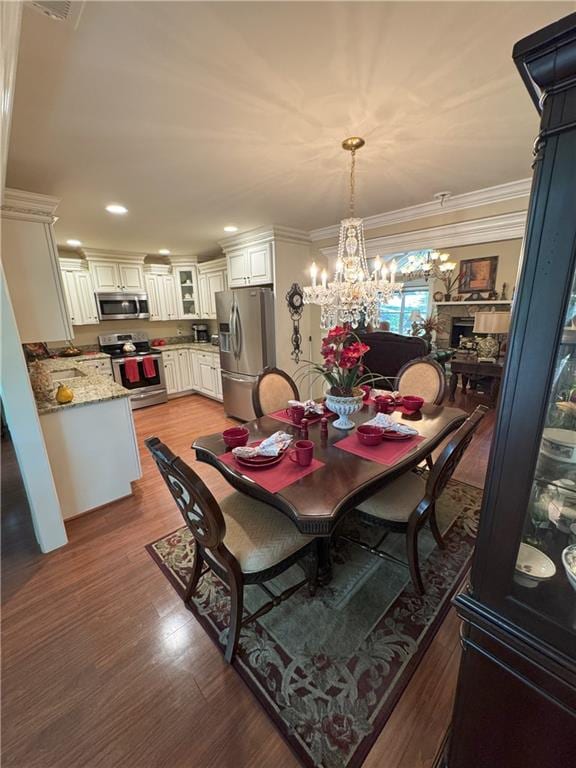 334 Eagle Cir, Dillard, GA 30537 - dining space featuring a chandelier, wood finished floors, ornamental molding, a fireplace, and recessed lighting
