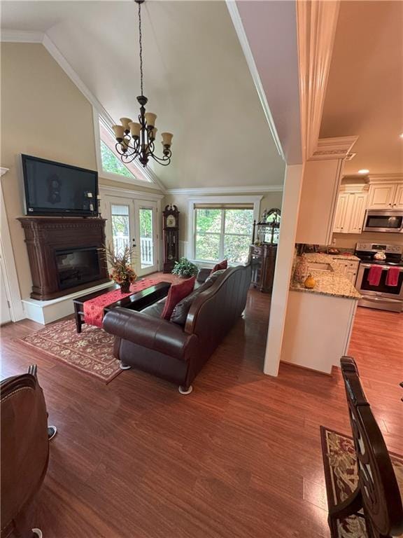334 Eagle Cir, Dillard, GA 30537 - living area featuring wood finished floors, vaulted ceiling, a glass covered fireplace, a chandelier, and crown molding