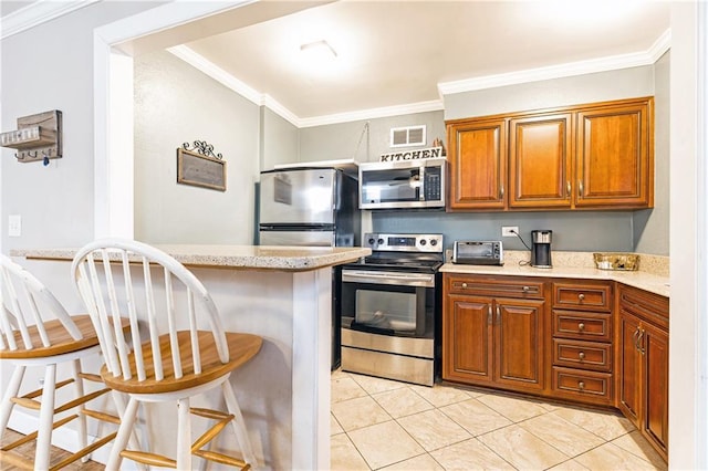 kitchen with a kitchen breakfast bar, crown molding, visible vents, appliances with stainless steel finishes, and brown cabinets