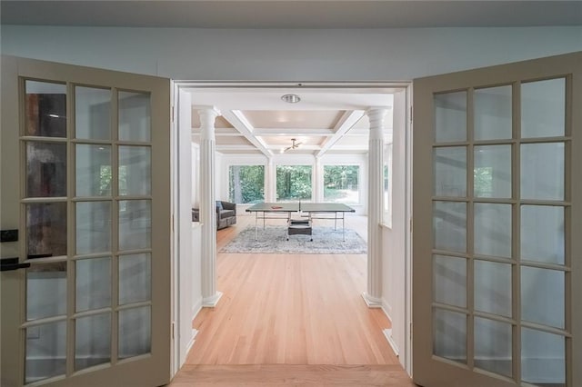 doorway to outside featuring coffered ceiling, decorative columns, and light wood-type flooring