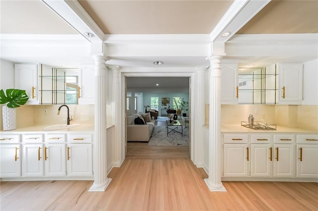 bar featuring white cabinetry, light hardwood / wood-style floors, sink, and a healthy amount of sunlight