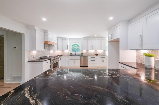 kitchen with white cabinets, sink, tasteful backsplash, appliances with stainless steel finishes, and dark stone countertops