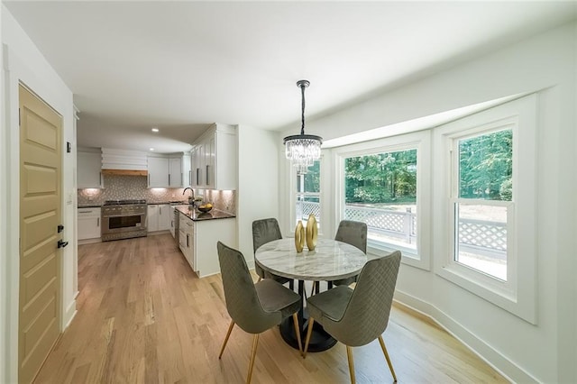 dining room with an inviting chandelier, sink, and light hardwood / wood-style floors