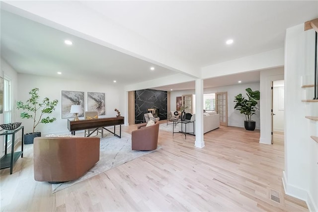 living room featuring beamed ceiling, light wood-type flooring, and a premium fireplace