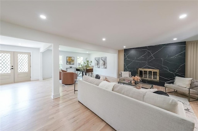 living room with a premium fireplace, french doors, tile walls, and light hardwood / wood-style flooring