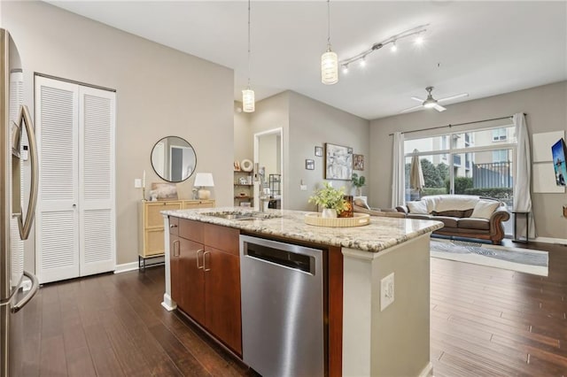 kitchen with pendant lighting, dark wood-type flooring, stainless steel appliances, and a center island with sink