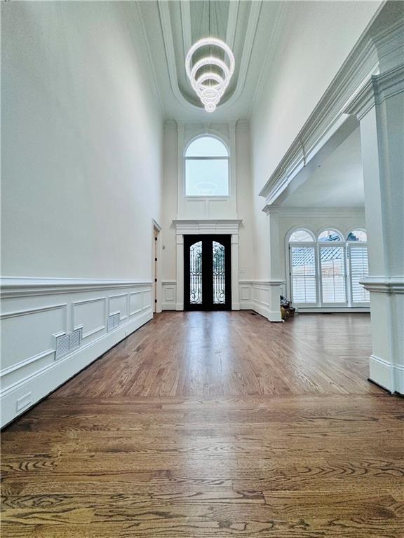 foyer entrance featuring ornamental molding, french doors, plenty of natural light, and an inviting chandelier