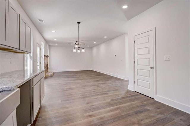 kitchen featuring light stone countertops, dark wood-type flooring, ceiling fan, and gray cabinets