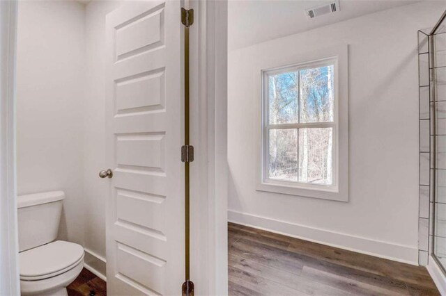 bathroom featuring wood-type flooring, a healthy amount of sunlight, and toilet