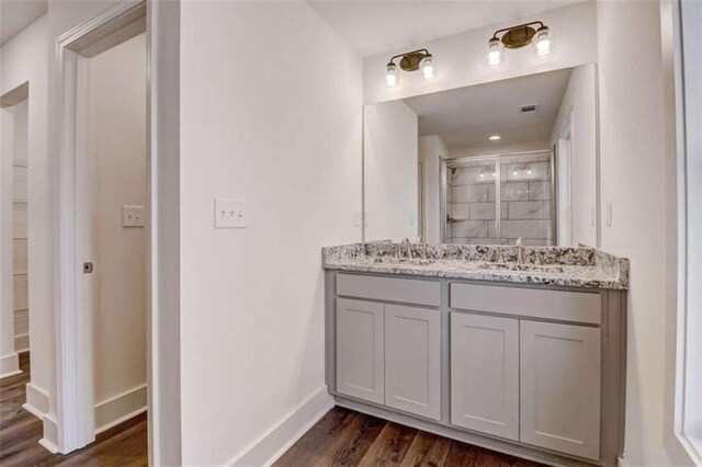 bathroom with walk in shower, vanity, and hardwood / wood-style flooring