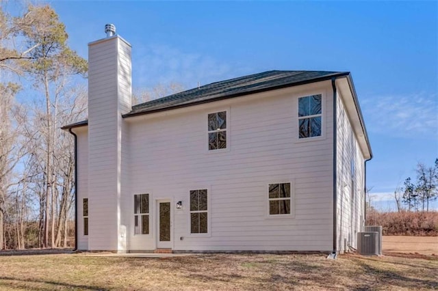 rear view of property with a lawn and central air condition unit