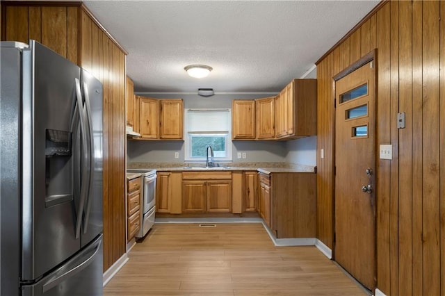 kitchen featuring white electric stove, sink, light hardwood / wood-style floors, stainless steel fridge with ice dispenser, and a textured ceiling