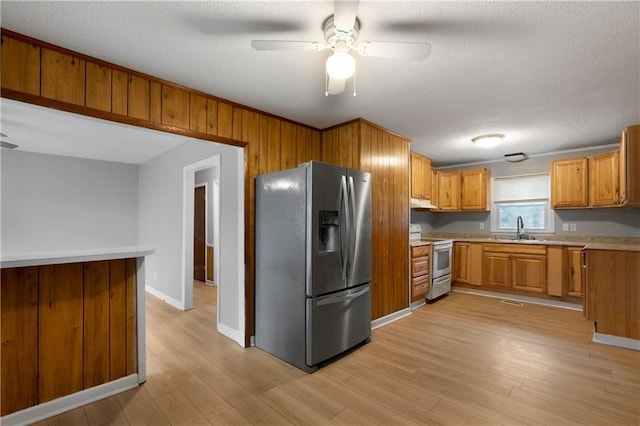 kitchen featuring sink, white electric range oven, stainless steel fridge, and light hardwood / wood-style floors