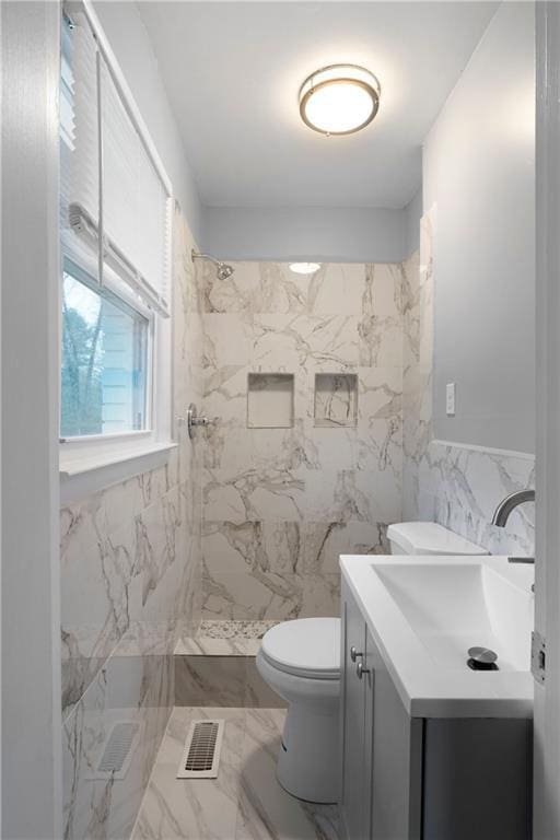 bathroom featuring vanity, tile walls, toilet, and tiled shower