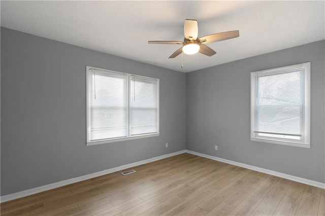 unfurnished room with ceiling fan, light wood-type flooring, and a wealth of natural light