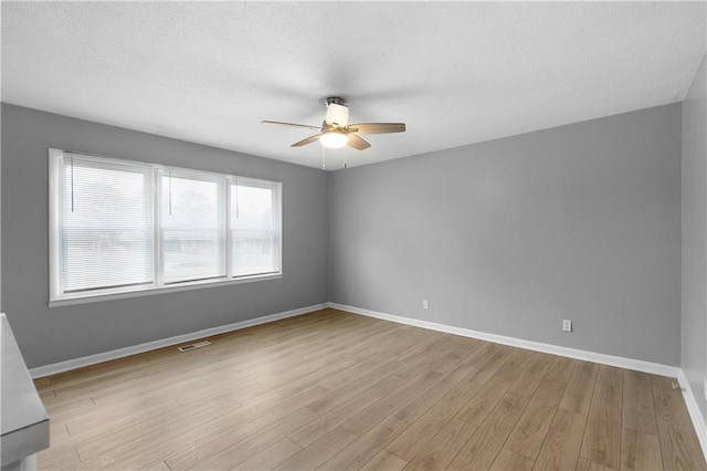 spare room with ceiling fan, a textured ceiling, and light wood-type flooring