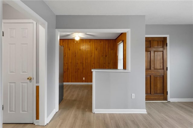 unfurnished room featuring light wood-type flooring and wood walls