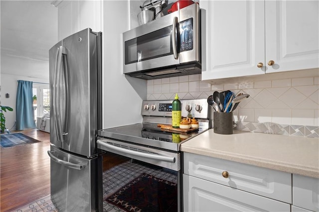 kitchen with stainless steel appliances, wood-type flooring, decorative backsplash, and white cabinets