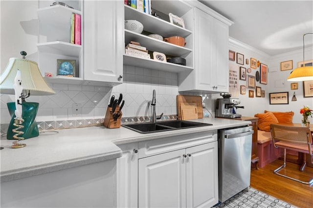 kitchen featuring stainless steel dishwasher, crown molding, white cabinets, and hanging light fixtures