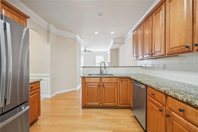 kitchen featuring appliances with stainless steel finishes, light stone counters, sink, and light wood-type flooring