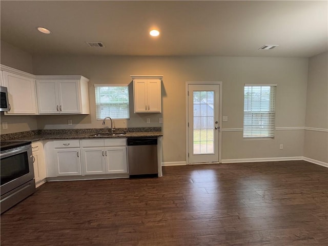 kitchen featuring stainless steel appliances, visible vents, dark wood-type flooring, white cabinetry, and a sink