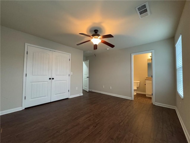 unfurnished bedroom with dark wood-style flooring, visible vents, and baseboards