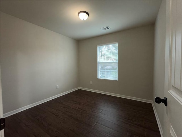 empty room with visible vents, dark wood finished floors, and baseboards