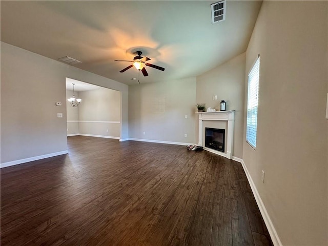 unfurnished living room with dark wood-style floors, ceiling fan with notable chandelier, a glass covered fireplace, and visible vents