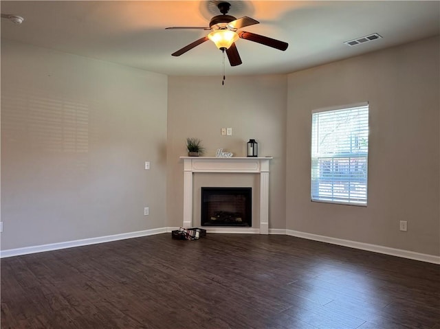 unfurnished living room with dark wood-type flooring, visible vents, and baseboards