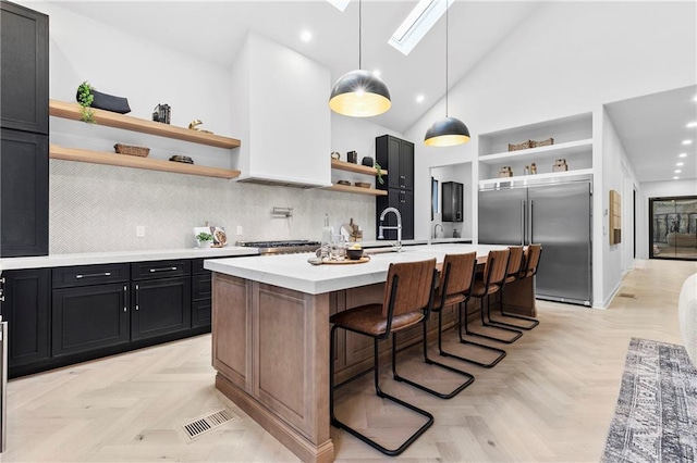 kitchen with visible vents, open shelves, light countertops, dark cabinets, and stainless steel built in refrigerator