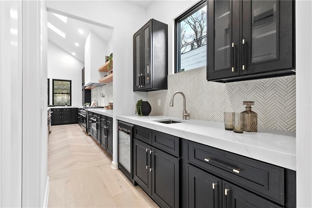 kitchen with plenty of natural light, a sink, decorative backsplash, wine cooler, and glass insert cabinets