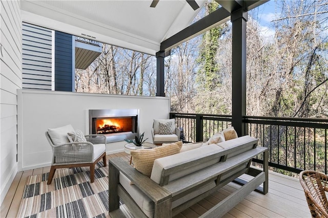 wooden deck with an outdoor living space with a fireplace