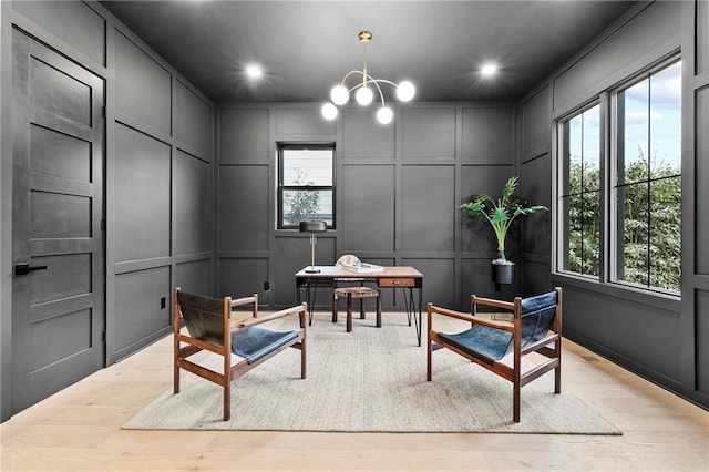 sitting room with a decorative wall, recessed lighting, an inviting chandelier, and wood finished floors