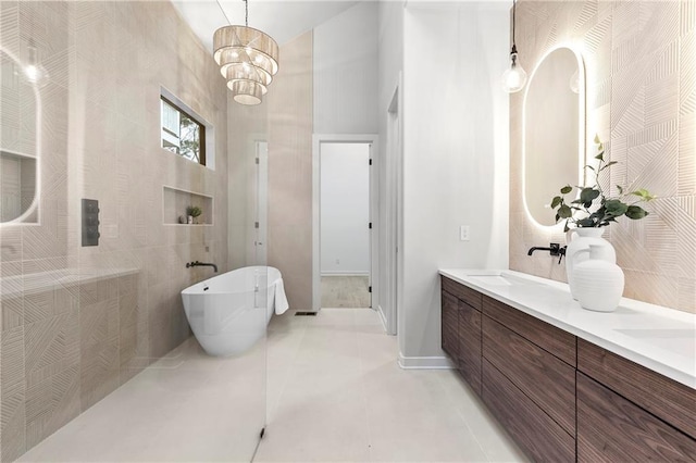 bathroom with a soaking tub, double vanity, a sink, tile patterned flooring, and a notable chandelier