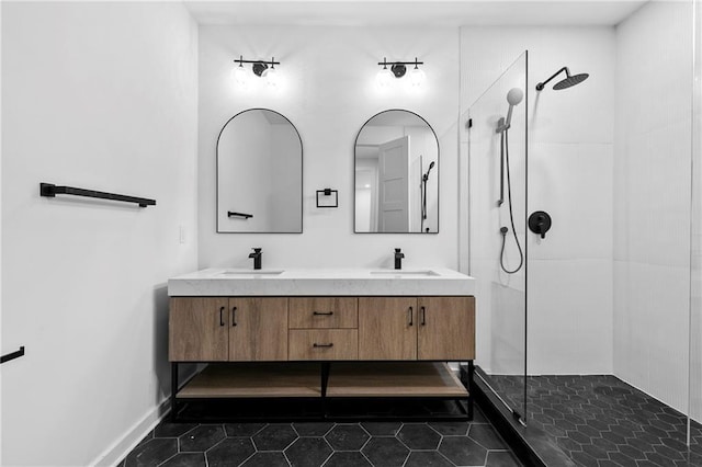 full bathroom with tile patterned floors, double vanity, a tile shower, and a sink