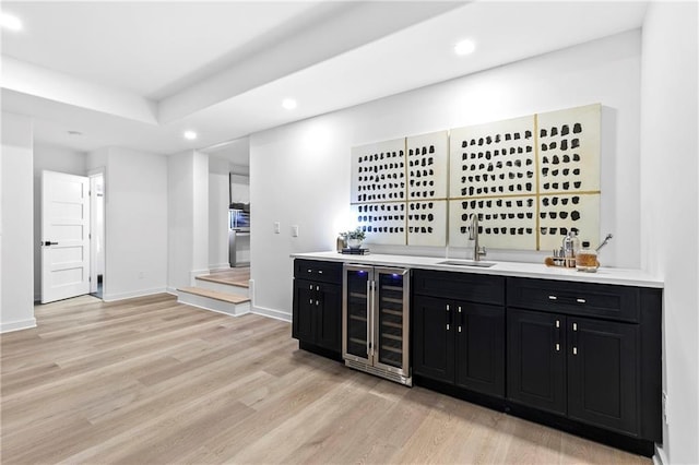 bar featuring beverage cooler, light wood-style flooring, a sink, recessed lighting, and indoor wet bar