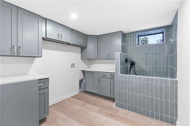 interior space with cabinet space, baseboards, light wood-style floors, and washer hookup