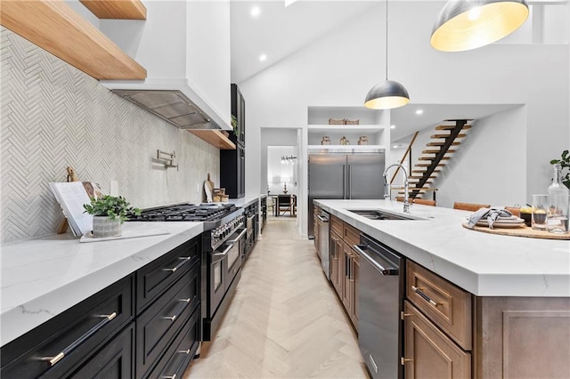 kitchen with light stone counters, open shelves, a sink, custom range hood, and premium appliances