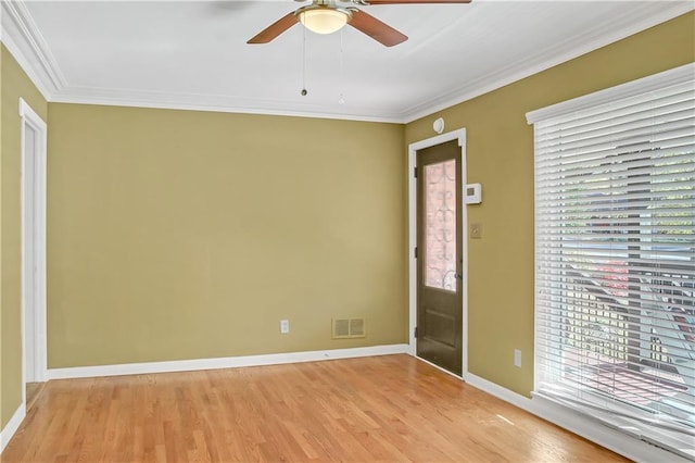 unfurnished room featuring a ceiling fan, visible vents, baseboards, ornamental molding, and light wood-type flooring