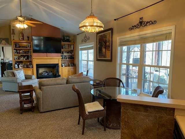 789 N Falling Waters Dr N, Demorest, GA 30535 - living area featuring a fireplace, vaulted ceiling, ceiling fan, carpet flooring, and a chandelier