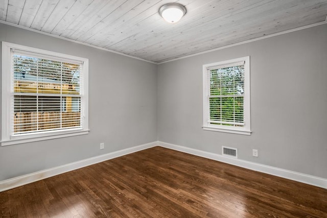 empty room with baseboards, visible vents, crown molding, and wood finished floors