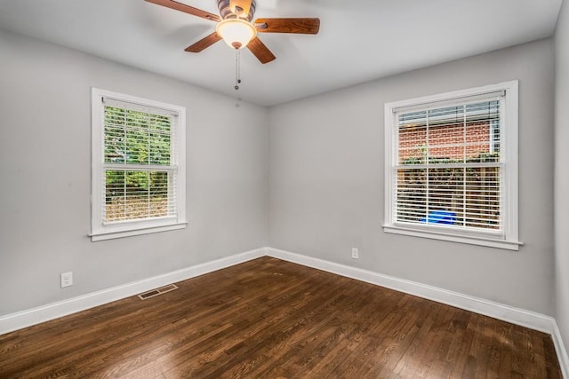 spare room with a ceiling fan, baseboards, visible vents, and dark wood-type flooring